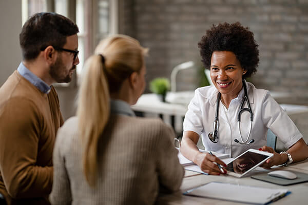 Happy black physician talking black couple