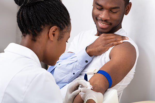 Image of black female physician injecting male patient