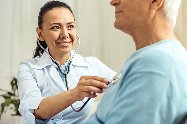 Joyful young physician examining elderly patient